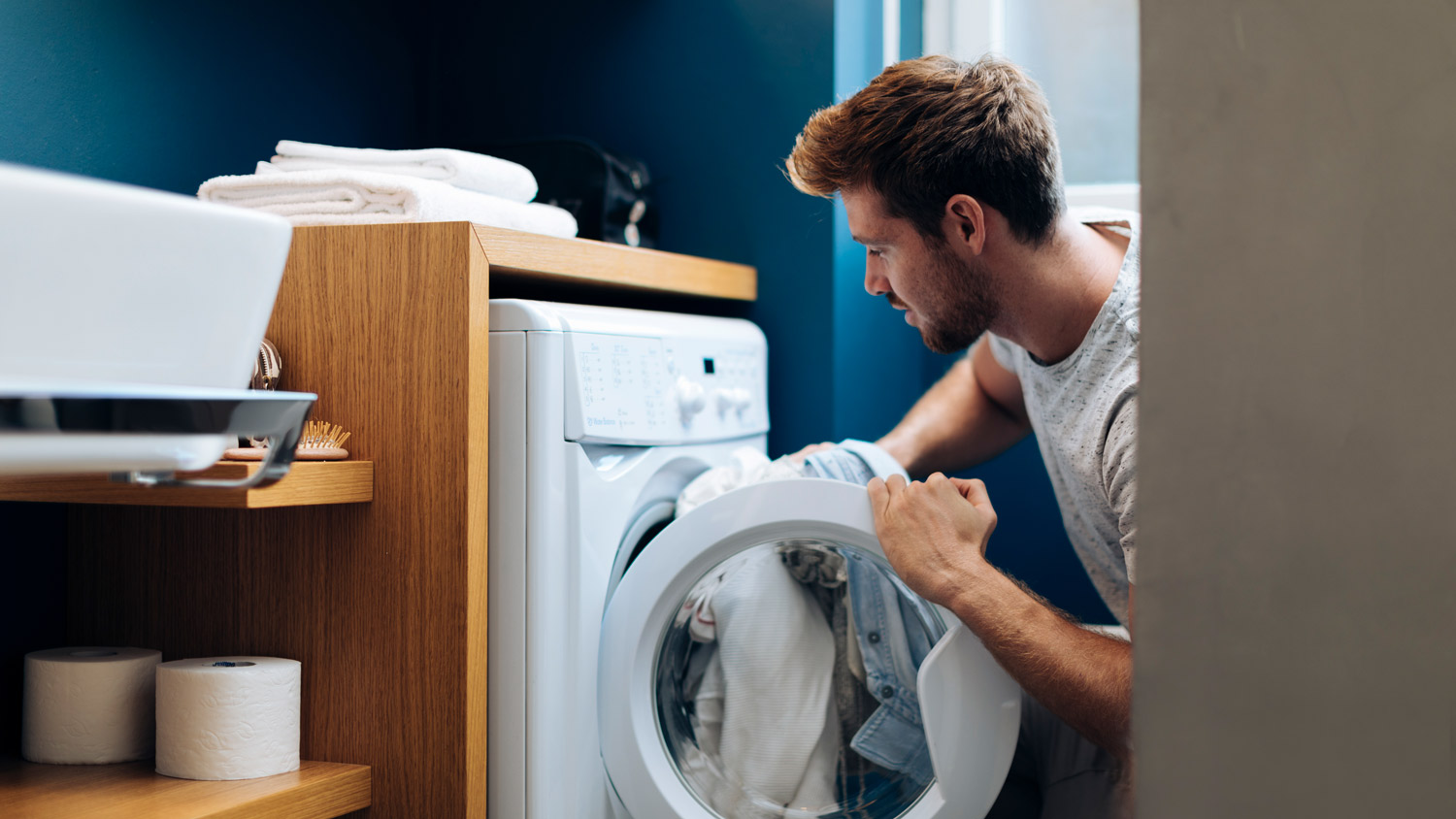 A young man doing the laundry at his home